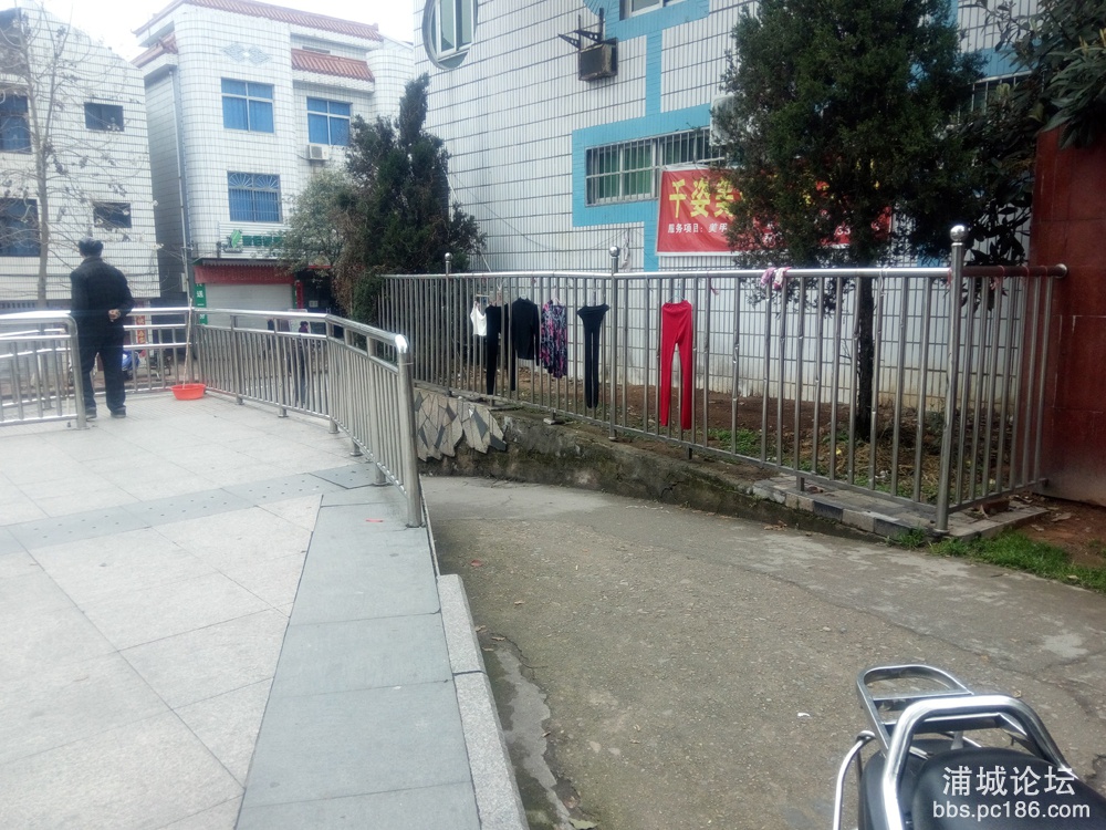 方志敏广场左侧一隅常年有市民在栏杆上晾晒衣服、被单，甚至内衣裤，随意侵占公共设施.jpg